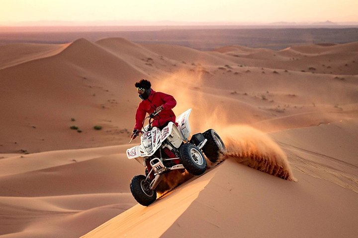 Experience the rush of quad biking across endless sand dunes where the sunset paints the desert landscape and the thrill of adventure awaits every rider.